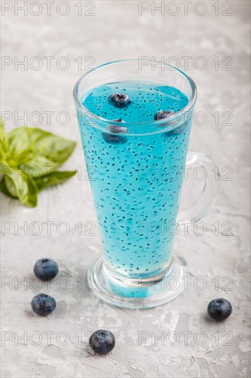 Glass of blueberry blue colored drink with basil seeds on a gray concrete background. Morninig, spring, healthy drink concept. Side view, close up