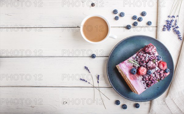 Berry cake with milk cream and blueberry jam on blue ceramic plate with cup of coffee and fresh blueberries on a white wooden background. top view, flat lay, copy space