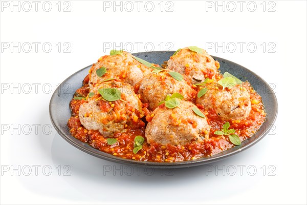 Pork meatballs with tomato sauce, oregano leaves, spices and herbs on blue ceramic plate isolated on white background. side view, close up