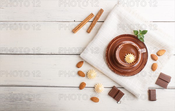 Cup of hot chocolate and pieces of milk chocolate with almonds on a white wooden background with linen napkin. top view, flat lay, copy space
