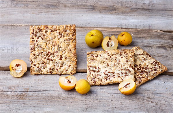 Biscuits with flax, sesame and sunflower seeds and yellow quince fruit on a rustic wooden background