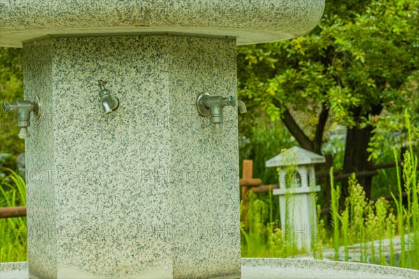 Large hand washing water fountain in a public park with lush green foliage in South Korea