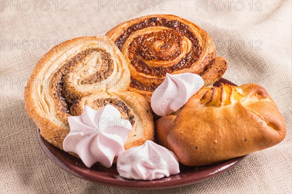 Sweet buns and meringues on a wooden board and linen tablecloth