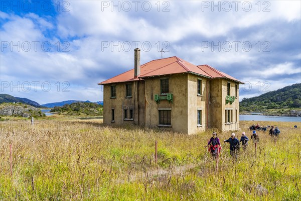 Hikers in front of the museum at a historic Yaghan aboriginal settlement, Wulaia Bay, Navarino Island on the Murray Channel, Patagonia, Chile, South America