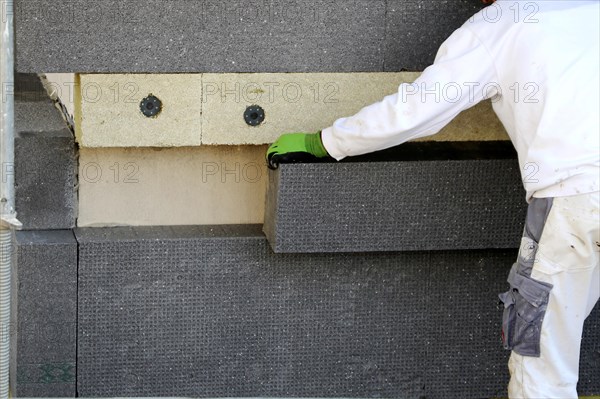 Construction workers insulate a house facade