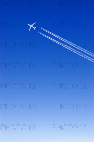 A passenger plane with vapour trails high in the blue sky