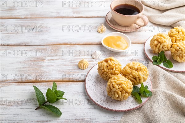 Traditional Tatar candy chak-chak made of dough and honey with cup of coffee on a white wooden background and linen textile. Side view, copy space