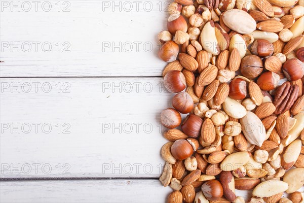Mixed different kinds of nuts on white wooden background. hazelnut, brazil nut, almond, pumpkin seeds, cashew. with copy space, top view