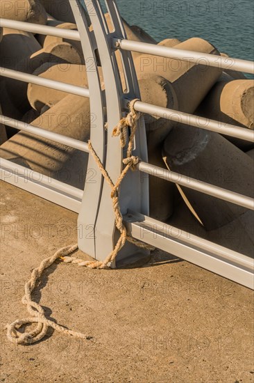 Length of rope tied around railing on harbor pier in South Korea