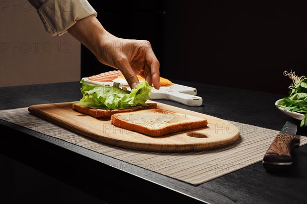 Unrecognizable woman makes sandwich with salad leaves