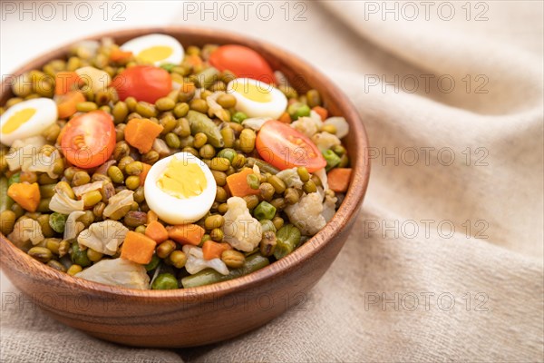 Mung bean porridge with quail eggs, tomatoes and microgreen sprouts on a white wooden background and linen textile. Side view, close up, selective focus