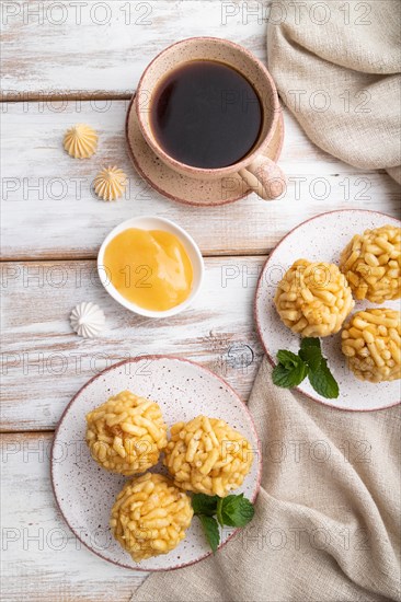 Traditional Tatar candy chak-chak made of dough and honey with cup of coffee on a white wooden background and linen textile. top view, flat lay, close up