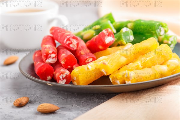 Set of various traditional turkish delight (rahat lokum) in blue ceramic plate with cup of coffee on a gray concrete background. side view, close up, selective focus