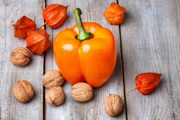 Walnuts, orange pepper and red physalis on rustic wooden background with copy space