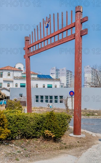 Decorative gate over entrance to Confucian school in Yuseong-gu with city buildings in background in Daejeon, South Korea, Asia