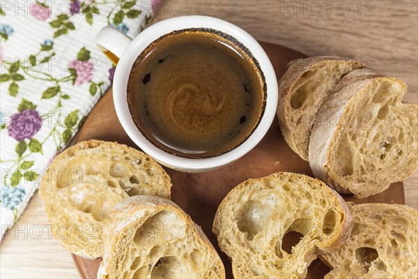 Sliced bread and a cup of coffee on a wooden board and linen tablecloth