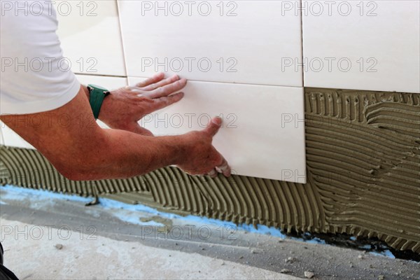 Tiler lays tiles on the wall