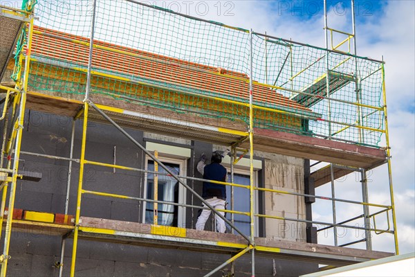 Construction workers insulate a house facade