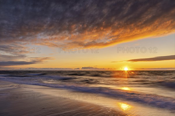 Sunset with illuminated clouds on the west beach near Prerow as a long exposure