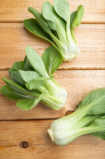 Fresh green bok choy or pac choi chinese cabbage on a brown wooden background. Top view, close up, flat lay