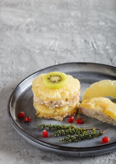 Pieces of baked pork with pineapple, cheese and kiwi on gray plate, side view, close up, selective focus, copy space