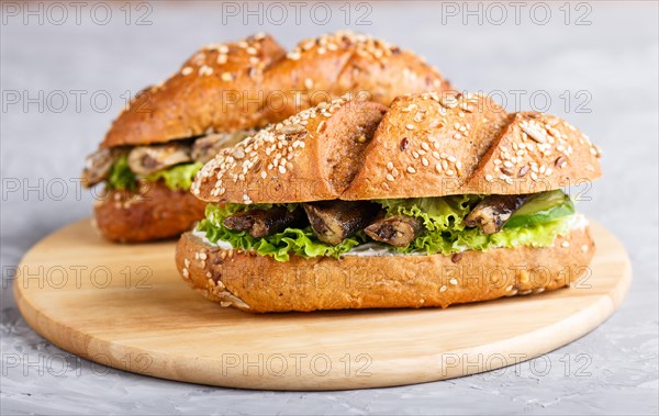 Sprats sandwiches with lettuce and cream cheese on wooden board on a gray concrete background. side view, close up