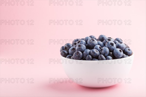 Fresh blueberry in white bowl on pink background. side view, copy space