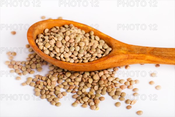 Pile of green lentils in a wooden spoon isolated on white background. Closeup