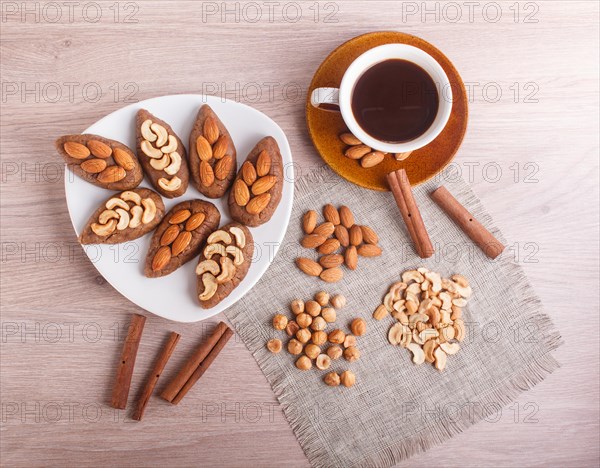 Small cakes potatoes with almonds and cashew nuts on a dessert plate. A cup of coffee, cinnamon, almonds, hazelnuts, cashew on a linen napkin. Still life. Copy space