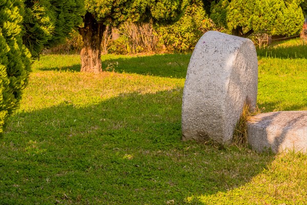 Giant millstone in lawn of green grass on sunny afternoon in public park in South Korea