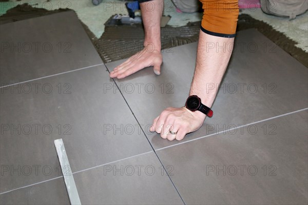 Tiler lays modern large floor tiles in a bathroom