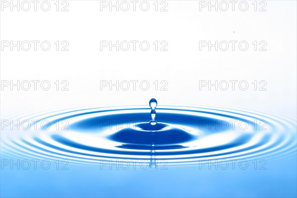 A drop of water jumps upwards from the water surface