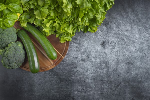 Fresh lettuce, courgettes and broccoli arranged on a wooden board symbolises health