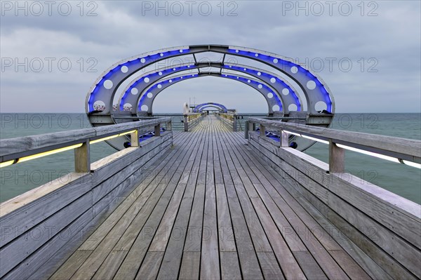 Long exposure of the Kellenhusen pier on the Baltic Sea with blue illuminated arcades