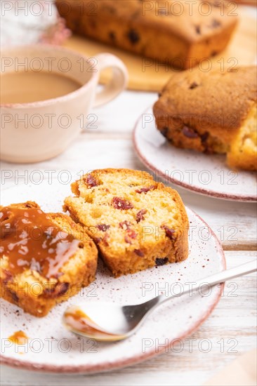 Homemade cake with raisins, almonds, soft caramel and a cup of coffee on a white wooden background. Side view, close up, selective focus