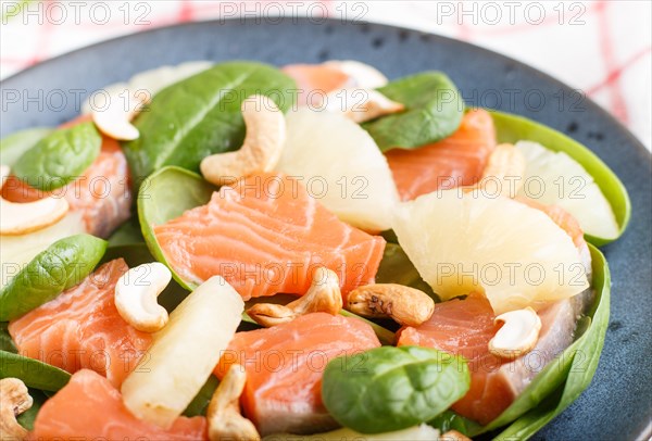 Fresh salmon with pineapple, spinach and cashew on a gray concrete background. Side view, close up, selective focus, linen tablecloth