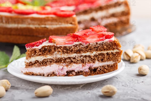 Homemade cake with yoghurt cream, strawberry, pistachio and a cup of coffee on a gray concrete background. side view, selective focus, close up