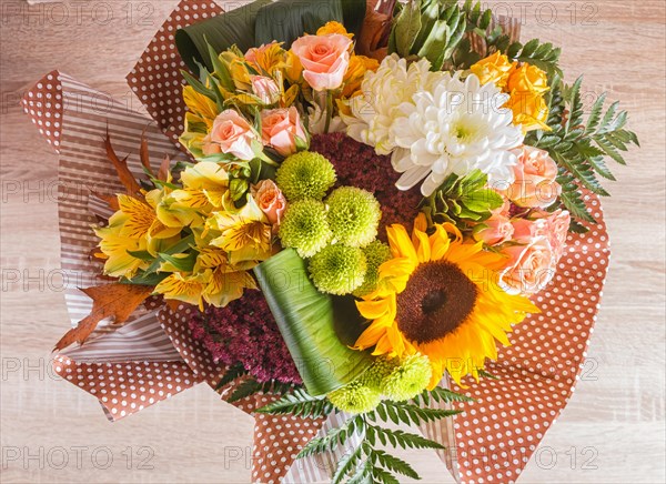 Bouquet of alstroemeria, sunflower, roses, chrysanthemum on a wooden background. floristic composition