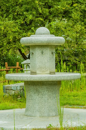 Large hand washing water fountain in a public park with lush green foliage in South Korea