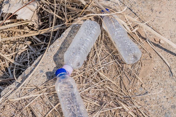 Three plastic water bottles left on concrete walkway in wilderness park in South Korea