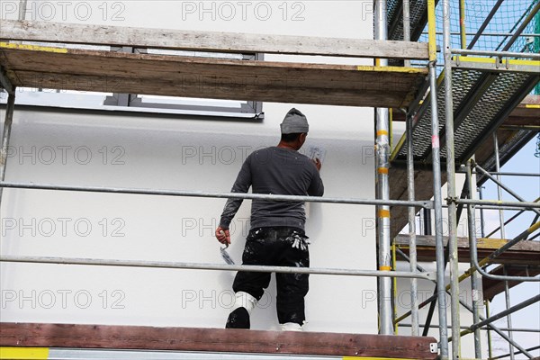 Painter and plasterer working on the facade of a new residential building (Mutterstadt development area, Rhineland-Palatinate)