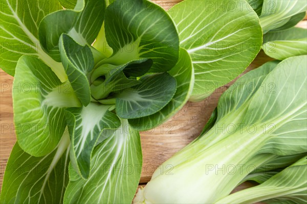 Fresh green bok choy or pac choi chinese cabbage on a brown wooden background. Top view, close up, flat lay