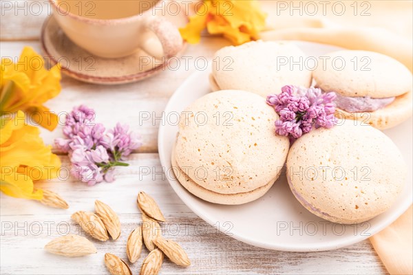 Meringues cakes with cup of coffee on a white wooden background and orange linen textile. Side view, close up, selective focus