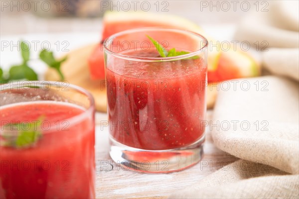 Watermelon juice with chia seeds and mint in glass on a white wooden background with linen textile. Healthy drink concept. Side view, close up, selective focus