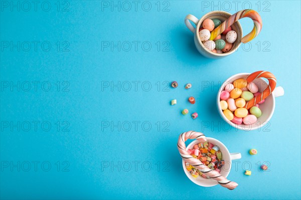 Heap of multicolored caramel candies in cups on blue pastel background. copy space, top view, flat lay