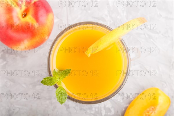 Glass of peach juice on a gray concrete background. Morninig, spring, healthy drink concept. Top view, close up, flat lay