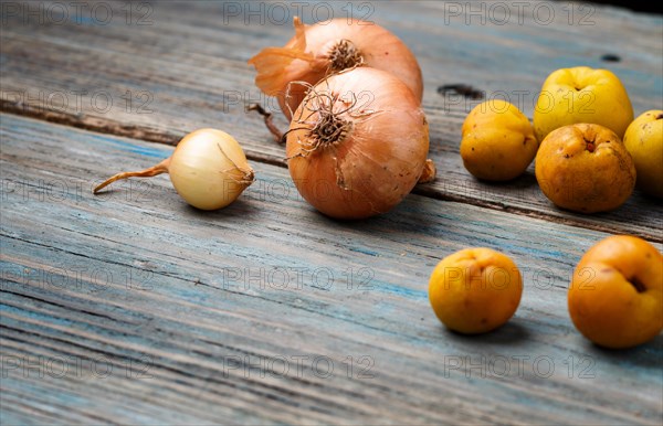 Fresh yellow fruits and onions on a blue rustic wooden background. Concept of contrast