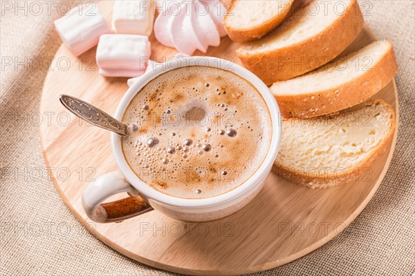 Sweet buns, meringues and coffee cup on a wooden board and linen tablecloth