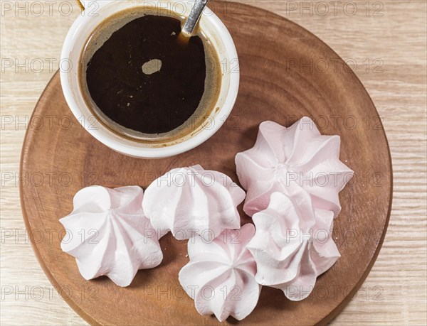 Chewing marshmallows, meringue and coffee cup on a wooden board and linen tablecloth
