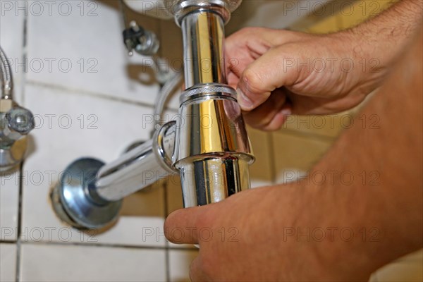 Plumber installs the siphon on a washbasin